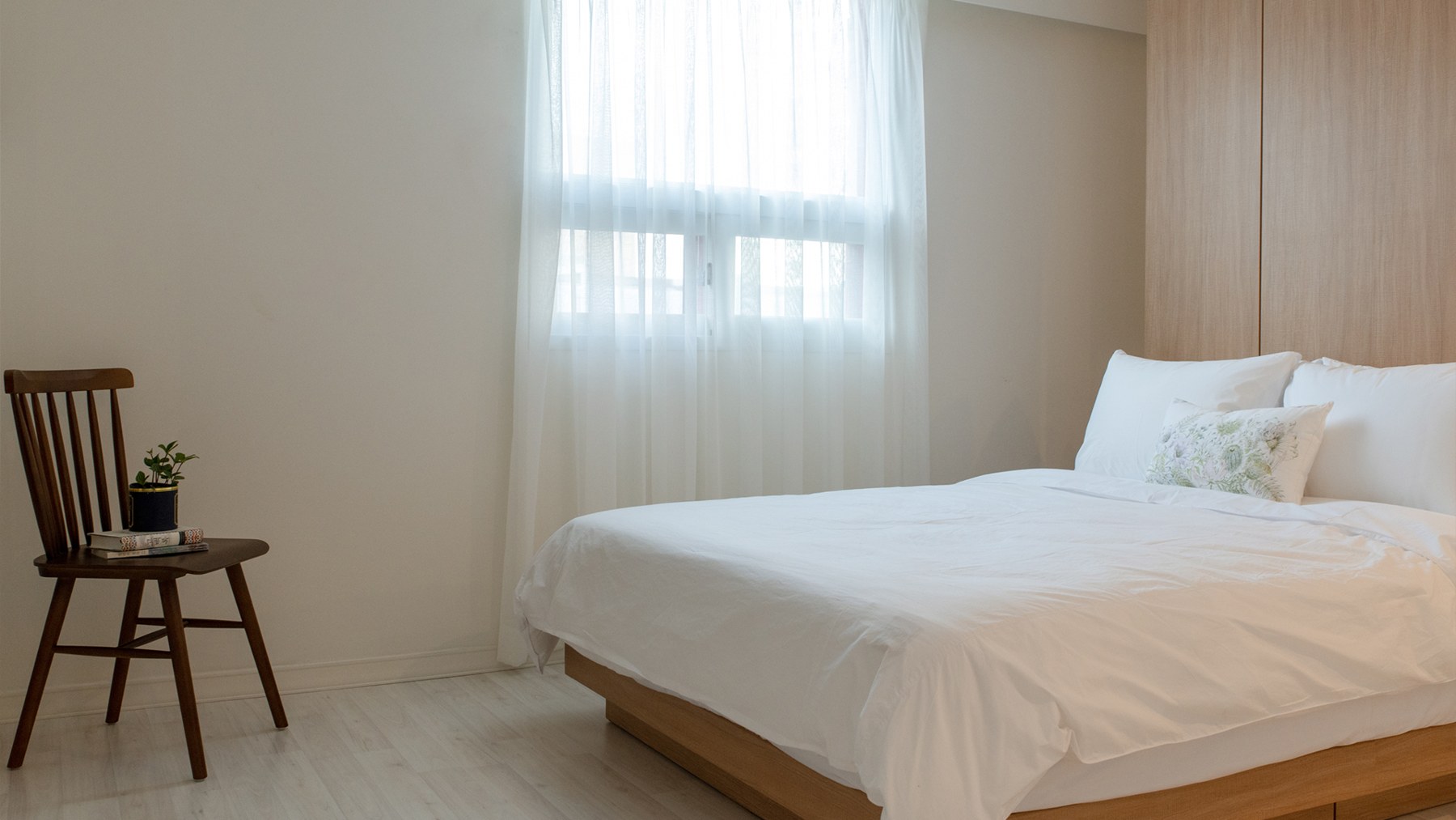 A Kyungsung Hotel guest room with a bed by the window and a wooden chair.