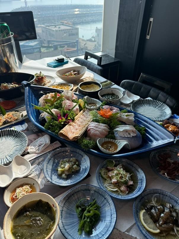 창가 테이블에 모둠회와 여러 곁들임 음식이 차려져 있다.