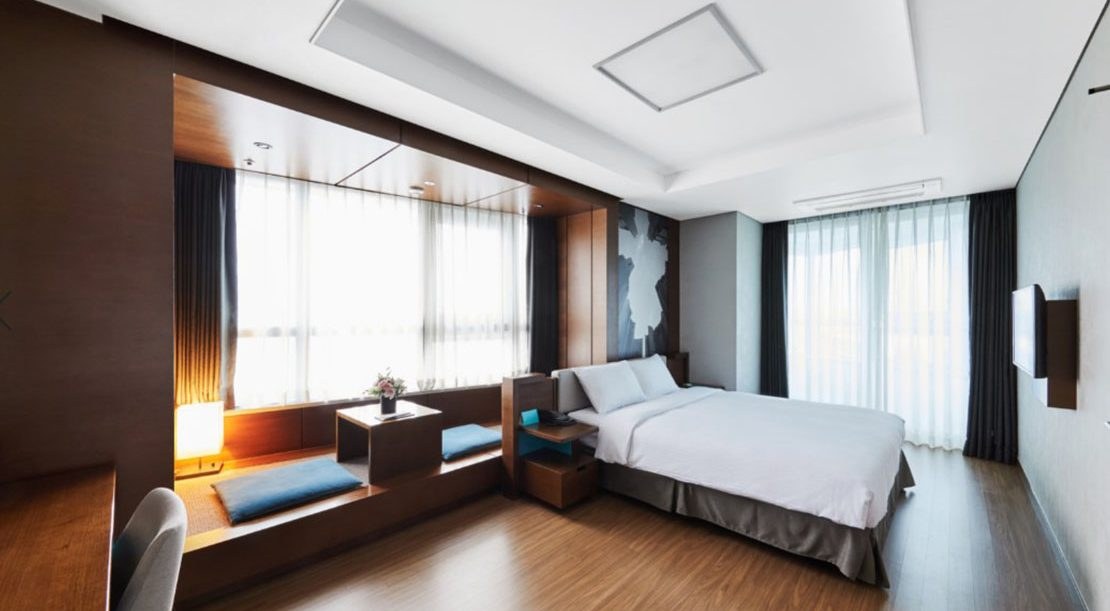 A Felix by STX guest room with large windows, window-side seating and a double bed.