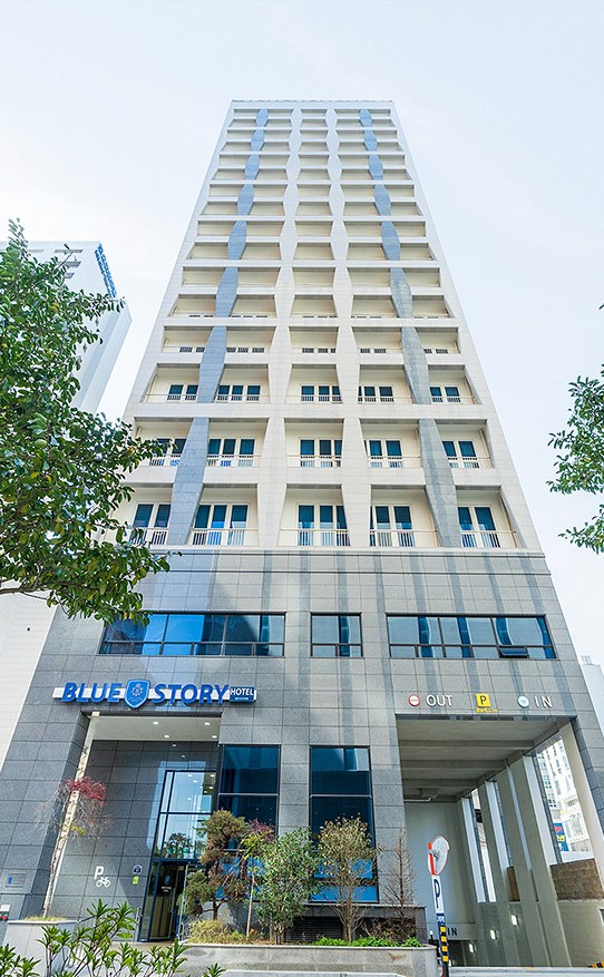 건물 입구와 주차장 진입로 위로 ‘BLUE STORY HOTEL’ 간판이 보이는 해운대 블루스토리 호텔 외관.