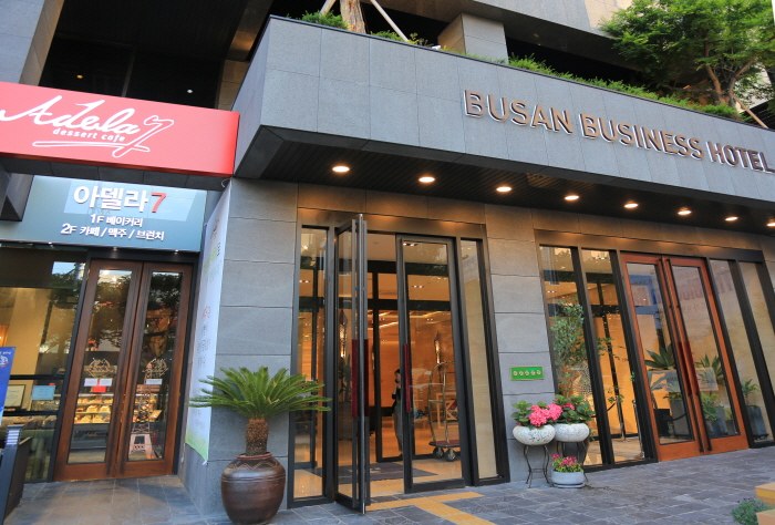 ‘BUSAN BUSINESS HOTEL’ 간판이 설치된 부산비즈니스호텔 출입구와 석재 외벽.