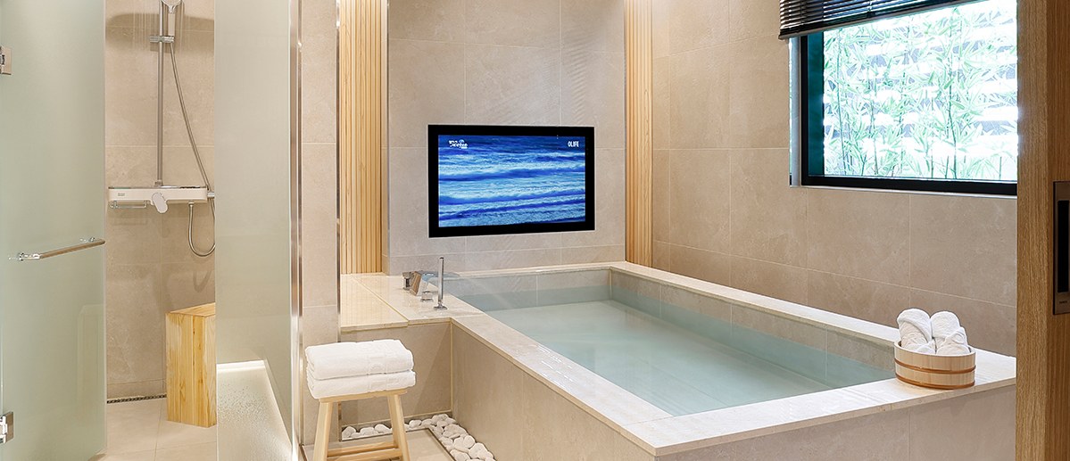 The Royal Pool Suite A bathroom, showing a rectangular tub, glass-partitioned shower and wall-mounted television.