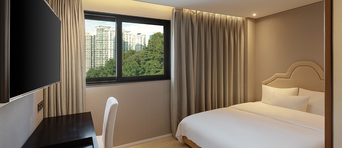 A Standard Double room at NewCZ Gwangan Hotel, showing a double bed, wall-mounted TV, desk, and window.