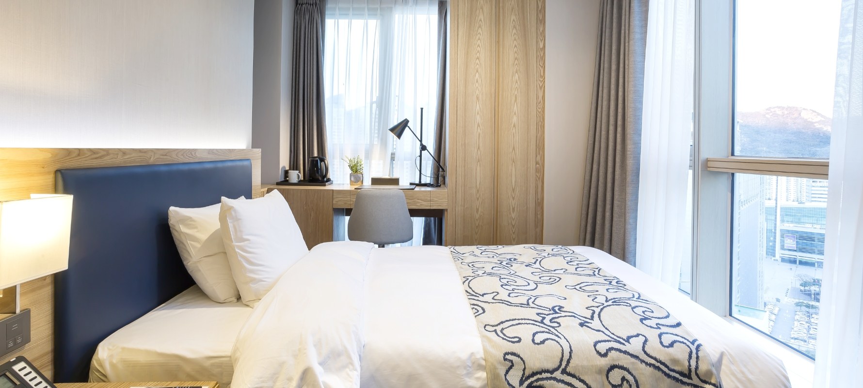 A Centum Premier Hotel single room with a bed, work desk, chair and windows.